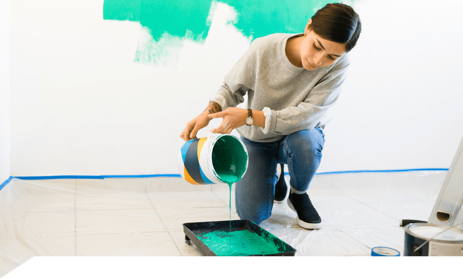 A woman crouched and pouring paint into a paint tray