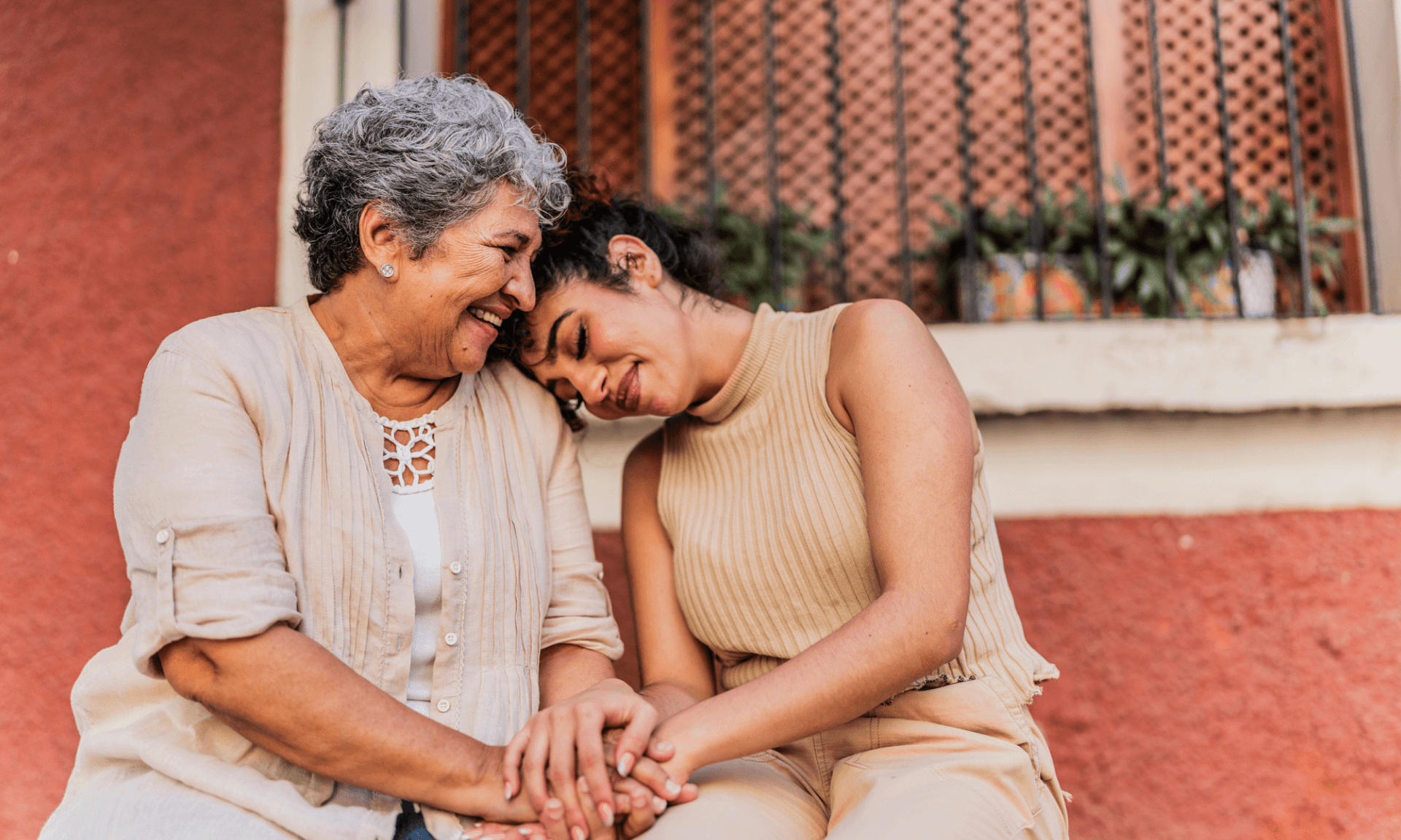 An elderly woman and a younger woman with her head on the elderly woman's shoulder